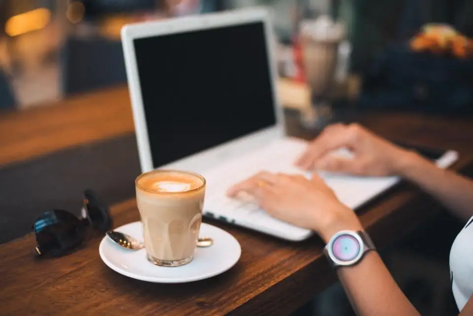 A laptop and a cup of coffee on a wooden table